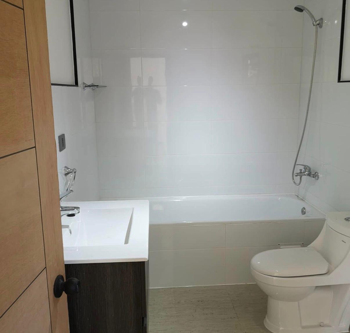 Sanitario WC y vanitorio flotante de madera instalados en baño con piso de porcelanato