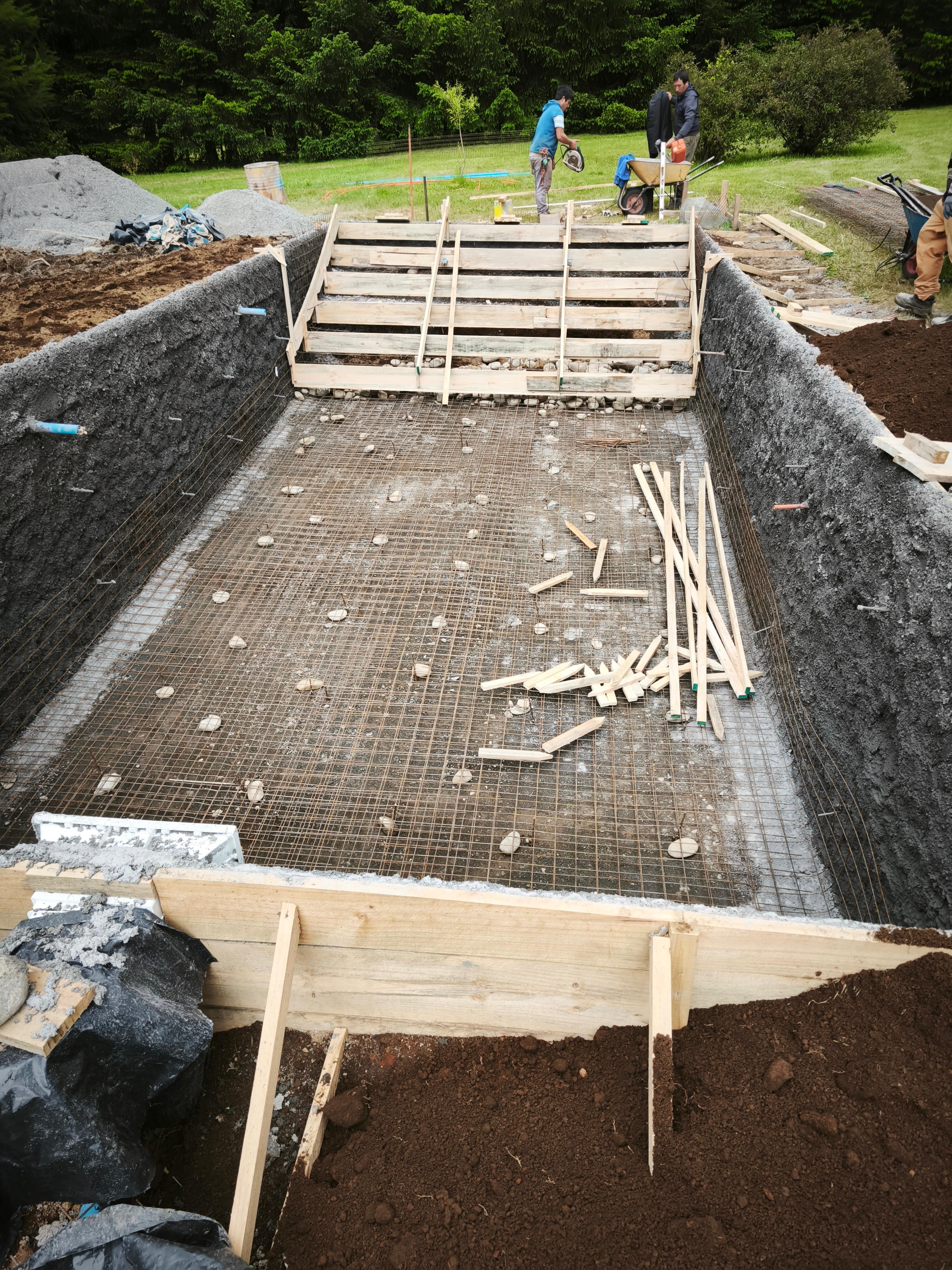 Aplicación de hormigón proyectado (shotcrete) en muros de piscina en construcción
